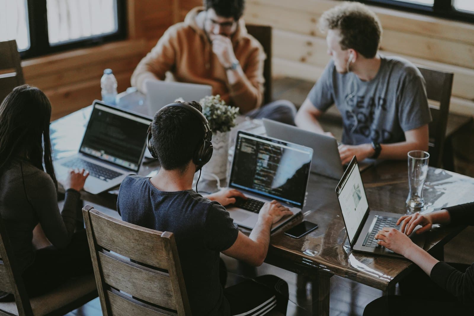 Engineers working together on laptops around a wooden table